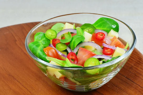 Salade de légumes frais dans un bol sur une planche de bois — Photo
