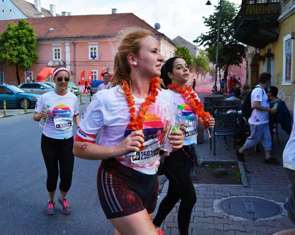 Belles jeunes filles éclaboussées de poudre colorée courir dans la rue — Photo