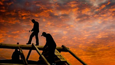 Roofers build cabin roof at dusk clipart