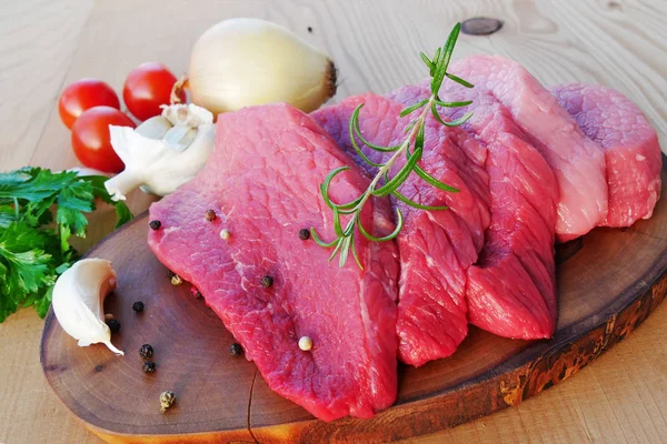 Sliced red meat on wooden board with herbs and spices — Stock Photo, Image