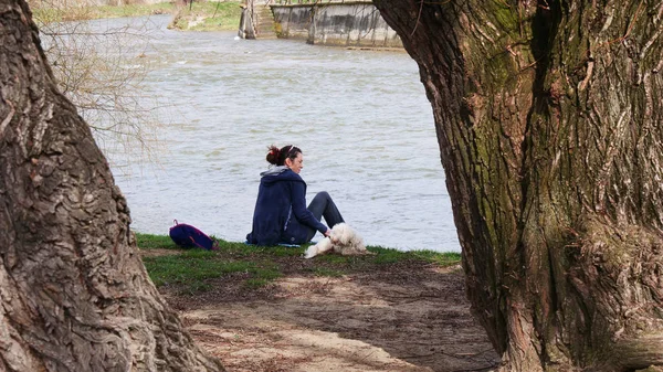 Ung kvinna och hennes hund koppla av vid floden — Stockfoto