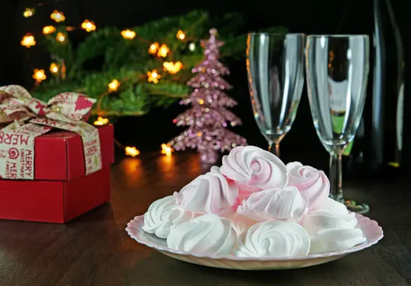 Meringue kisses cookies on plate, gift and champagne glasses — Stock Photo, Image