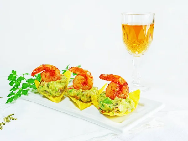 Canapes met guacamole en garnalen geserveerd op krokante tortilla chips op witte serveerplaat — Stockfoto