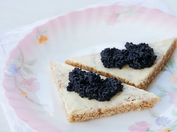 Černý kaviár na plátky chleba s máslem přes barevný talíř — Stock fotografie