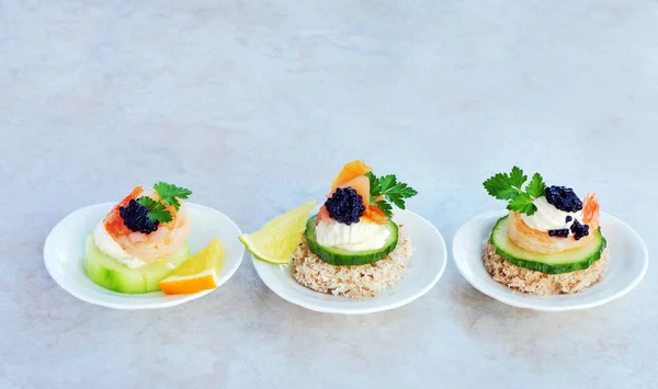 Canapés de fiesta con salmón ahumado, camarones y caviar negro en porcelana con forma de concha individual que sirve el plato sobre la mesa de mármol —  Fotos de Stock