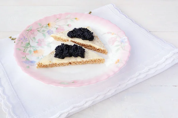 Caviar negro en rebanadas de pan con mantequilla sobre un plato colorido — Foto de Stock