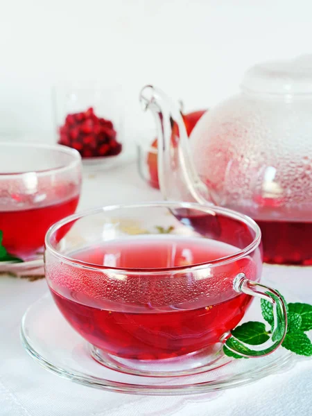 Granatäpple te i glas tekoppar och tekanna med mynta blad över vit bakgrund, vertikal — Stockfoto