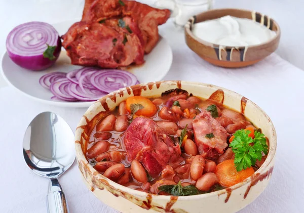 Пинто-бобовый суп с копченой ветчиной в миске со сметаной и красным луком — стоковое фото