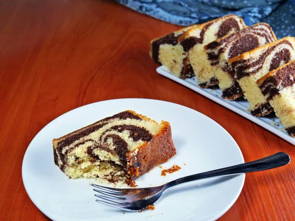 Fetta di torta di marmo al cioccolato su piatto bianco con un pezzo già mangiato . — Foto Stock