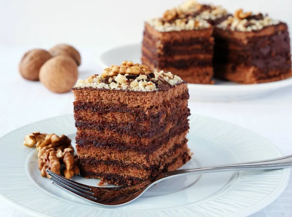 Pastel de chocolate en capas cuadrados con relleno de crema de chocolate y nuez en plato blanco — Foto de Stock