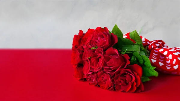 Κόκκινο τριαντάφυλλο μπουκέτο με μετάξι τόξο πάνω από το κόκκινο τραπέζι, δώρο επετείου με αντίγραφο χώρο — Φωτογραφία Αρχείου