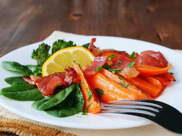 Cunhas de batata-doce assadas com pedaços de bacon frito, espinafre de bebê, brócolis e limão no prato — Fotografia de Stock