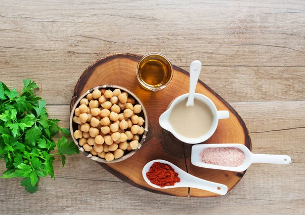 Hummus ingredients, chickpeas, tahini sauce, salt and olive oil  on wooden board — Stock Photo, Image