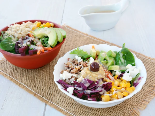 Deux bols de Bouddha avec des légumes, des grains sains et des protéines. Salade végétarienne saine avec bouillie de sarrasin, maïs, avocat et humus avec sauce tahini — Photo