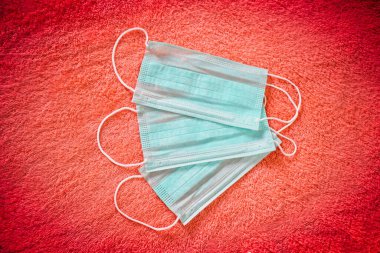 Kırmızı arka planda tıbbi koruyucu yüz maskesi ağız ve burnu kaplayan tek kullanımlık cerrahi maske. Sağlık ve Tıp Konsepti