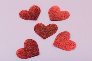 five red glitter hearts on pink background