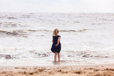 Deniz kıyısında oynayan sarışın kız.