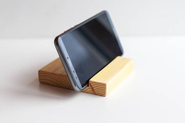 Telefon ahşap bir stantta beyaz bir arkaplanda.