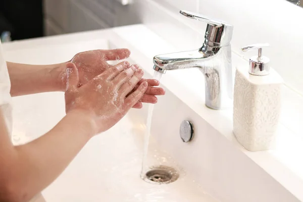 soaping hands with a white dispenser in the bathroom