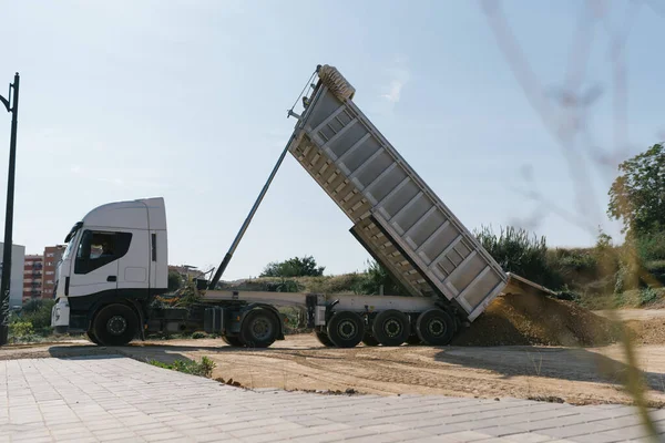 Toprak ve taşları taşıyan kamyon, açık araziye malzeme atıyor.