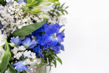 Yuvarlak bir kutuda parlak duygusal buket (renk: beyaz, mavi, yeşil. Çiçekler: Delphinium ve alstroemeria)