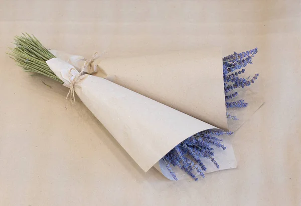 lavender flowers in a package of craft paper on a light beige background