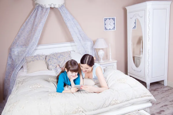 Ibu dan anak yang bahagia terbaring di tempat tidur dengan tablet digital . — Stok Foto