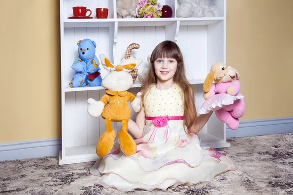 Malé radostné holčičky hrají s hračkami v jejím pokoji. — Stock fotografie