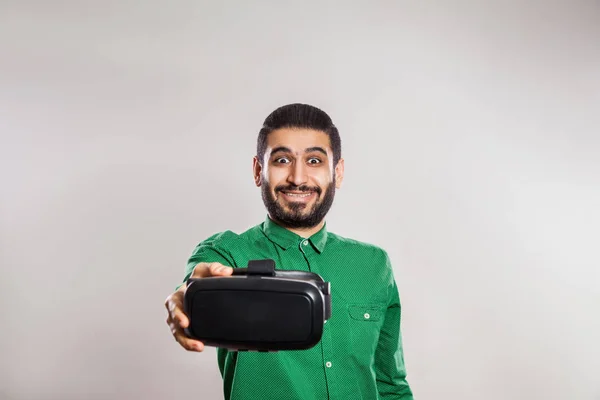 Junger emotionaler Mann aus dem Nahen Osten mit Bart und grünem Hemd, der ein vr-Headset benutzt und virtuelle Realität erlebt. — Stockfoto