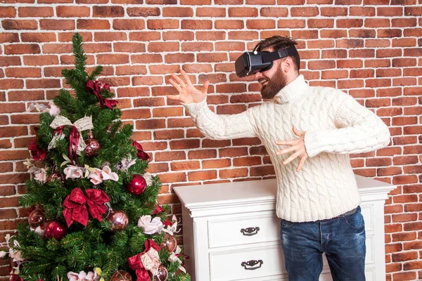 Ensamhet och illusionen av nytt år. porträttet av skäggig man med virtual reality-glasögon nära nyår träd. — Stockfoto