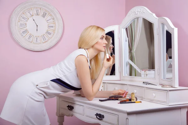 Jovem mulher loira bonita está se preparando e fazendo maquiagem na frente do espelho para namoro no dia dos namorados . — Fotografia de Stock