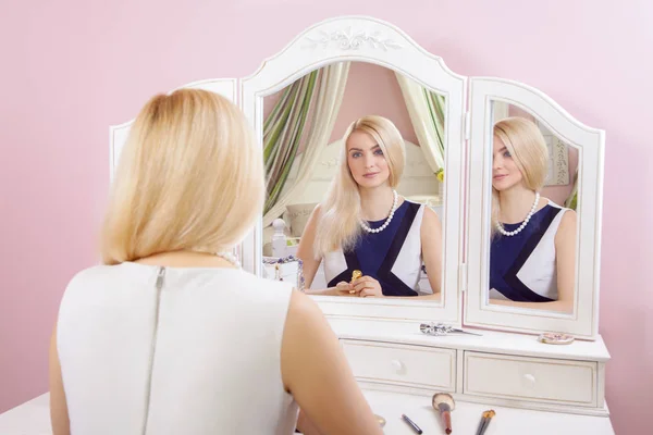 Молодая красивая блондинка готовится и делает макияж перед зеркалом для свиданий на День Святого Валентина . — стоковое фото