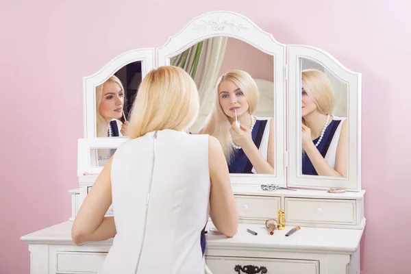 Jovem mulher loira bonita está se preparando e fazendo maquiagem na frente do espelho para namoro no dia dos namorados . — Fotografia de Stock