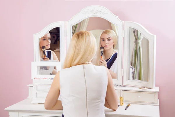 Joven hermosa mujer rubia se está preparando y haciendo maquillaje delante del espejo para citas en día de San Valentín . — Foto de Stock