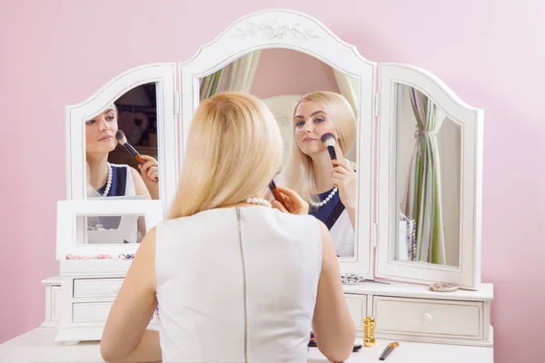 Молодая красивая блондинка готовится и делает макияж перед зеркалом для свиданий на День Святого Валентина . — стоковое фото