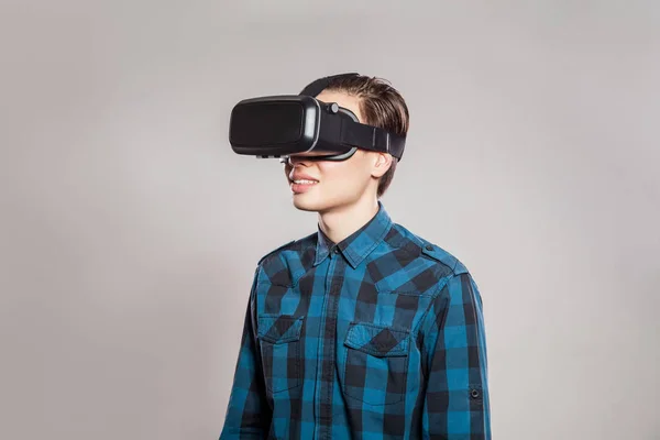 Emocjonalne zabawny człowiek ubrany wirtualnej rzeczywistości gogle. Portret Studio gry wideo projektanta noszenia Vr zestaw słuchawkowy. Studio strzał na białym tle na szarym tle. — Zdjęcie stockowe