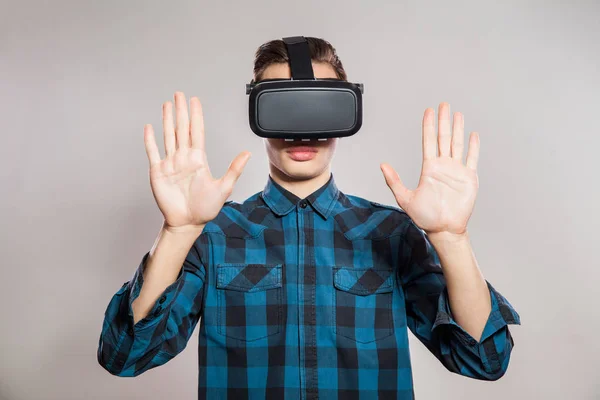 Pria lucu emosional mengenakan kacamata realitas maya. Potret studio perancang permainan video memakai headset VR. pengambilan gambar studio terisolasi di latar belakang abu-abu . — Stok Foto