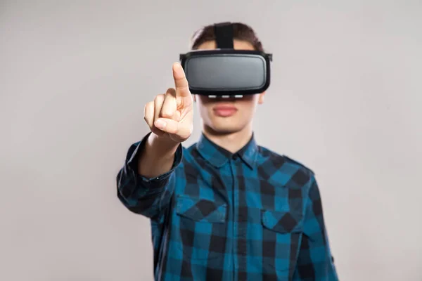 Pria lucu emosional mengenakan kacamata realitas maya. Potret studio perancang permainan video memakai headset VR. pengambilan gambar studio terisolasi di latar belakang abu-abu . — Stok Foto