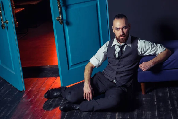 Modelo de moda jovem elegante em um terno perto da porta com luz vermelha. Estilo de negócio. Imagem elegante. Vestido de noite. Homem sexy de pé e olhando para a câmera. Look de moda . — Fotografia de Stock