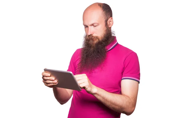 Tabletta és rózsaszín póló elszigetelt fehér background kopasz szakállas férfi portréja. — Stock Fotó