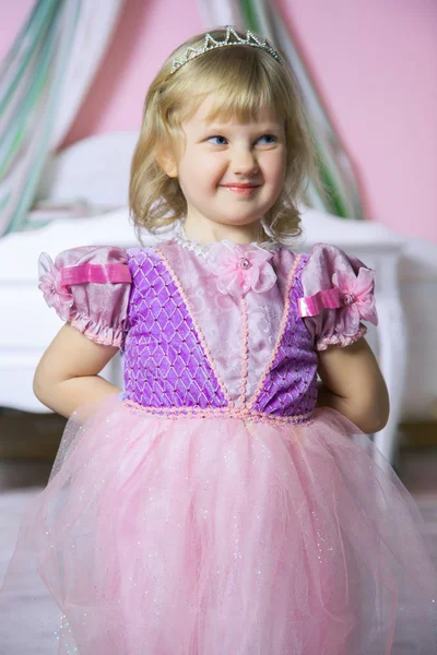 गुलाबी पोशाक में छोटी खुश राजकुमारी लड़की और अपने शाही कमरे में मुकुट और मुस्कुराते हुए . — स्टॉक फ़ोटो, इमेज