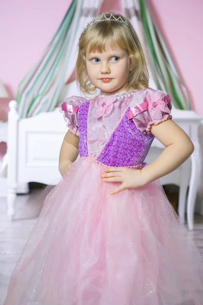 Šťastná princezna holčička v růžových šatech a koruny v pokoji královské lodě a usmívá se. — Stock fotografie