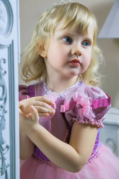 Little happy princess girl in pink dress and crown in her royal room posing and smiling. — Stock Photo, Image