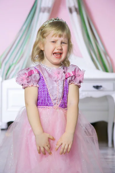 Trochu nešťastná princezna dívka v růžových šatech a koruny v pokoji královské pláče. — Stock fotografie