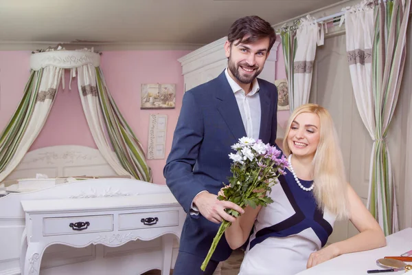 Jovem homem bonito surpreendendo sua bela namorada e dá-lhe buquê de flores brancas roxas . — Fotografia de Stock