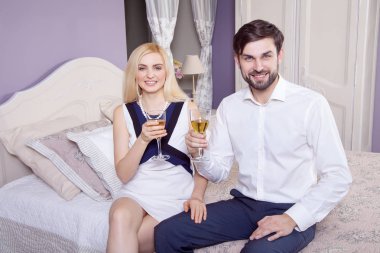 Güzel genç çift Sevgililer gün içinde birlikte eğleniyor. beyaz şarap içme ve onların iyi romantik tanışma yatağın üstüne oturan zevk.