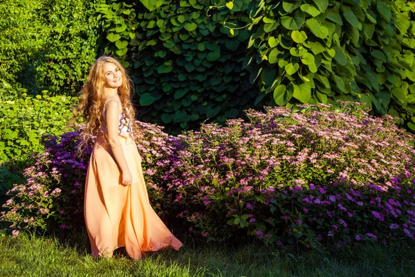 Glad vacker flicka med långa ljusbrunt hår poserar i parken. — Stockfoto