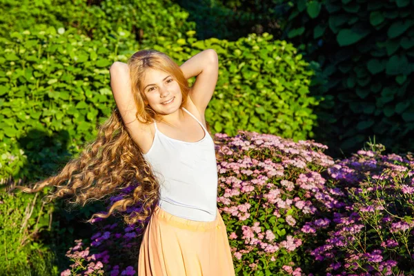 Menina bonita feliz com longos cabelos castanhos claros está posando no parque . — Fotografia de Stock