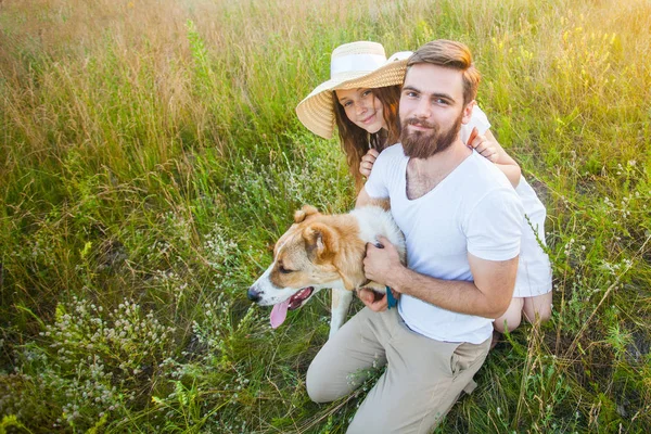 Happy beautiful couple with their Alabai dog in nature with sunset. — Stock Photo, Image