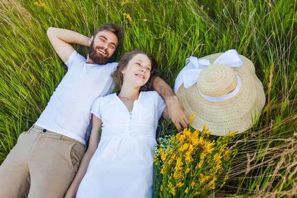 Happy young relaxed couple in love laying down on the grass overhead — Stock Photo, Image